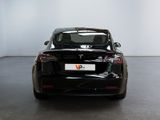 the back end of a black tesla vehicle in a white room