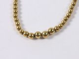 a close up of a gold beaded necklace on a white background