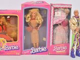 Trois poupées Barbie sont alignées les unes à côté des autres sur une surface blanche