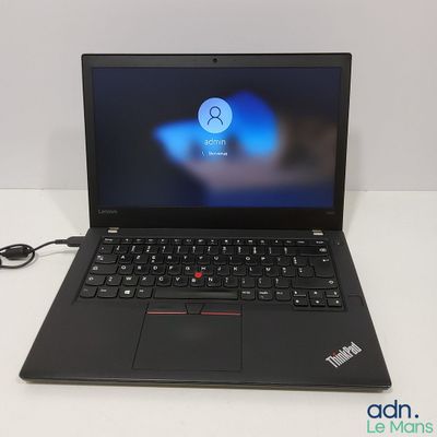 un ordinateur portable noir posé sur une table blanche