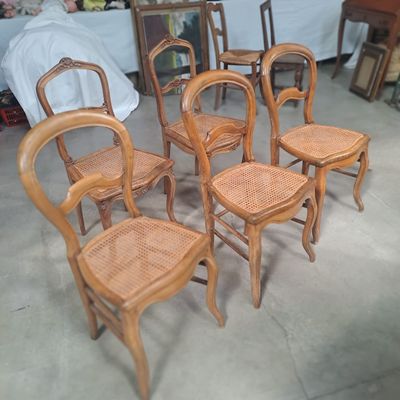 six chaises en bois disposées dans une pièce, avec un lit en arrière-plan
