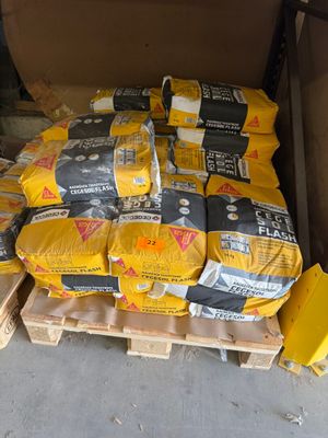 de nombreux sacs de ciment posés sur des palettes dans le garage