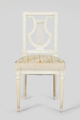 a white wooden chair with a beige upholstered seat