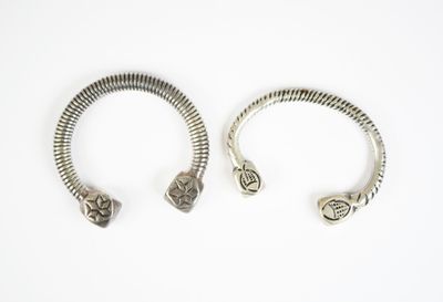 deux bracelets en argent posés sur une surface blanche, sur fond blanc
