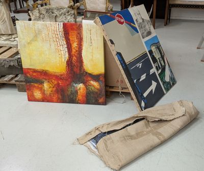 un tas d'œuvres d'art par terre, à côté d'une pile de livres