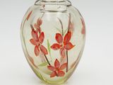 a glass vase with red flowers in it on a white surface