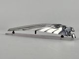 un objet en métal orné d'un oiseau, posé sur une table