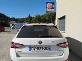 the back of a white car parked in front of a building