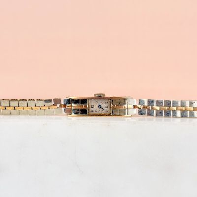 une image représentant une montre en or et en argent sur fond rose