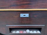 a wooden table with balls in it and a person reaching for the ball