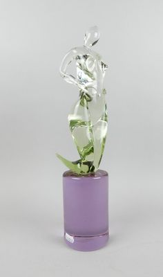 vase en verre violet contenant une plante verte, sur fond blanc