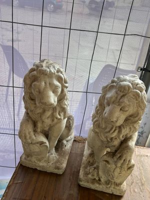two statues of lions sitting on a table in front of a window