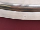 a silver plate with a handle on a red surface