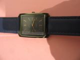 une montre noire et dorée montée sur un bracelet en cuir noir