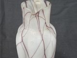 a white vase with red lines on it on a black background