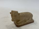 a small figurine of a cow on a white surface
