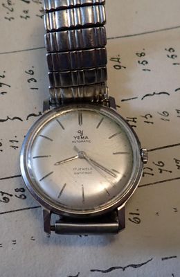 une montre en argent posée sur une feuille de papier