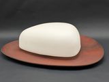 a white soap sitting on top of a wooden plate on a black surface