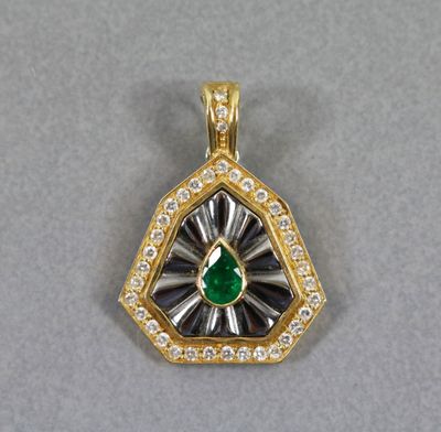 un gros plan d'un pendentif en forme de diamant vert et blanc posé sur une surface grise