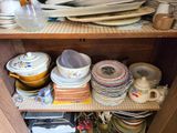 many plates and bowls stacked on a shelf in the kitchen