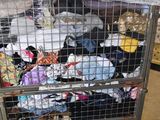 a metal cart filled with lots of clothes in a warehouse