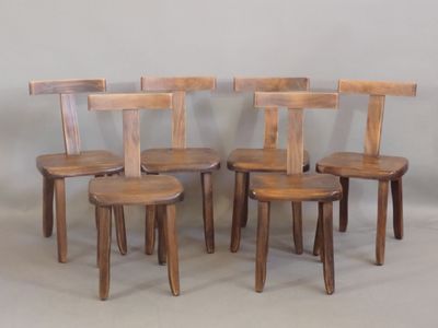 quatre chaises en bois disposées les unes à côté des autres sur une surface blanche