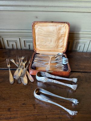 several silverware items are sitting on a wooden table with a case full of forks, spoons, and spoons