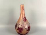 a small glass vase with leaves painted on it sitting on a table