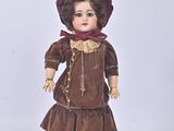 une poupée qui porte une robe marron et un chapeau