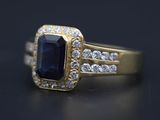 un gros plan d'une bague en or sertie d'une pierre bleue entourée de diamants blancs