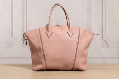 un sac à main en cuir rose posé sur une table en bois