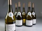 six bouteilles de vin blanc sont alignées sur une table