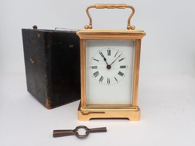 une petite horloge posée à côté d'une boîte contenant une clé