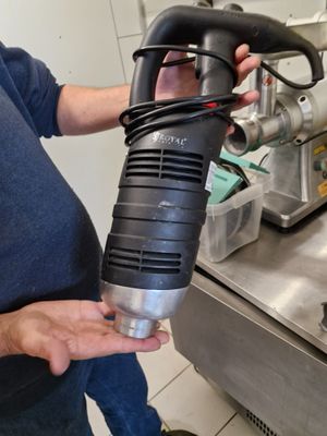 a man holding a black and silver blow dryer in a kitchen