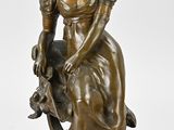 une statue antique en bronze représentant une femme assise sur une chaise