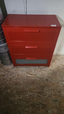 a red chest of drawers in the corner of a room