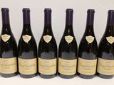 six bouteilles de vin sont alignées sur une table