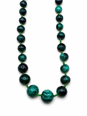 un gros plan d'un collier de perles vertes sur fond blanc