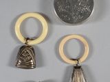 three pieces of silver and ivory jewelry with a coin in the background