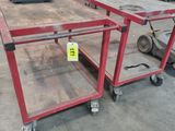 a red cart with two shelves on it in the middle of a warehouse