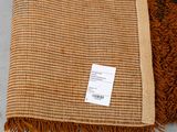 a close up of a brown and tan rug with a tag on it