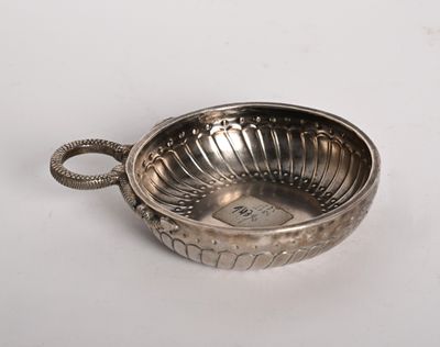 une assiette en argent antique avec une poignée sur une surface blanche