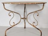 an old iron table with a marble top in a white room