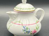 a small white tea pot with a bird on top of it