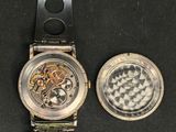 a watch and a coin sitting on a black surface