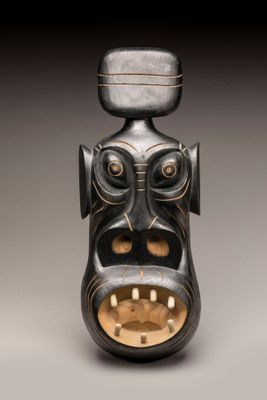 une image représentant un vase noir et doré orné d'un visage