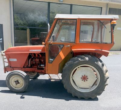 un petit tracteur orange garé devant un bâtiment