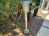 une lampe posée par terre près d'un buisson