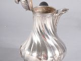 a silver pitcher with a handle on a stand