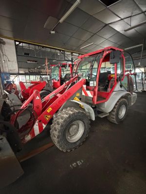a red tractor that is parked inside of a building